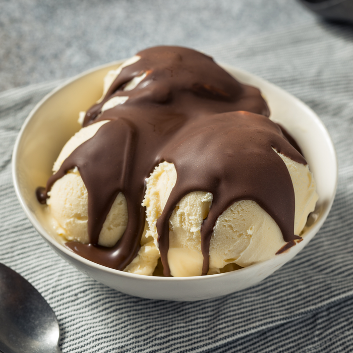 Drizzling fast-hardening Blommer chocolate ice cream coating over a gourmet ice cream sundae.
