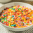 Creamy fruity cereal milk frozen yogurt swirl in a clear cup with cereal toppings
