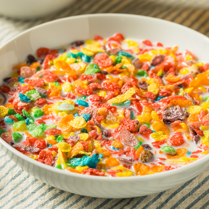 Creamy fruity cereal milk frozen yogurt swirl in a clear cup with cereal toppings