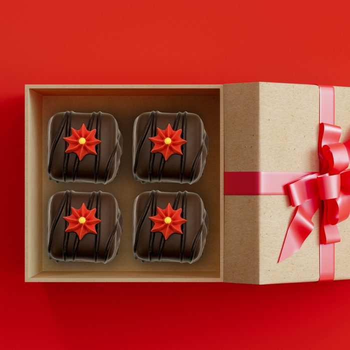 Close-up of a mini red royal icing poinsettia flower topping a gourmet holiday chocolates in a gift box by Caljava
