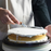 Professional baker spreading smooth 50Express white buttercream icing onto a layered cake