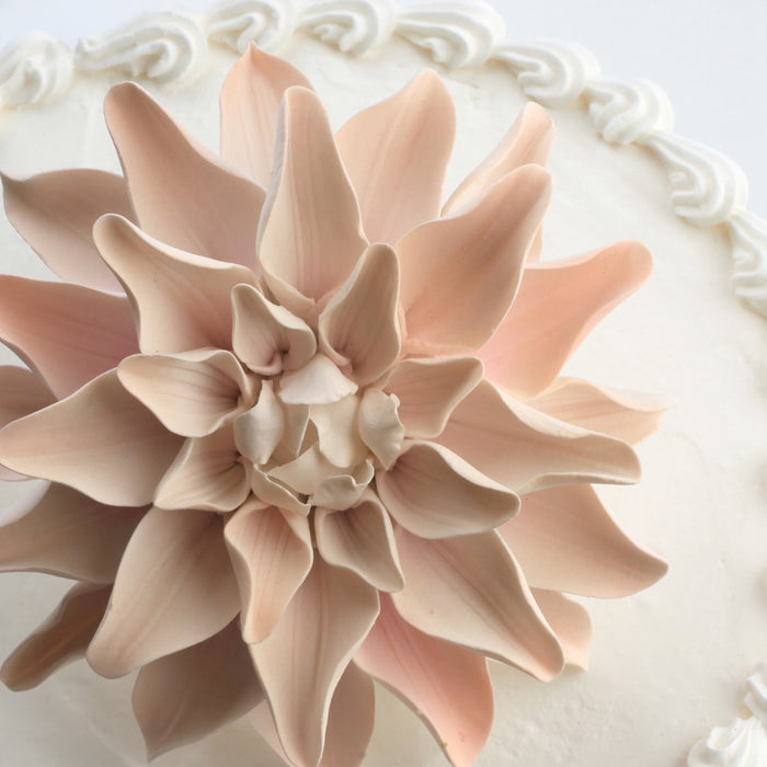 Peach gumpaste dahlia sugar flower positioned on a multi-tiered fondant wedding cakeWholesale sugarflower. Caljava Bakery Supplies
