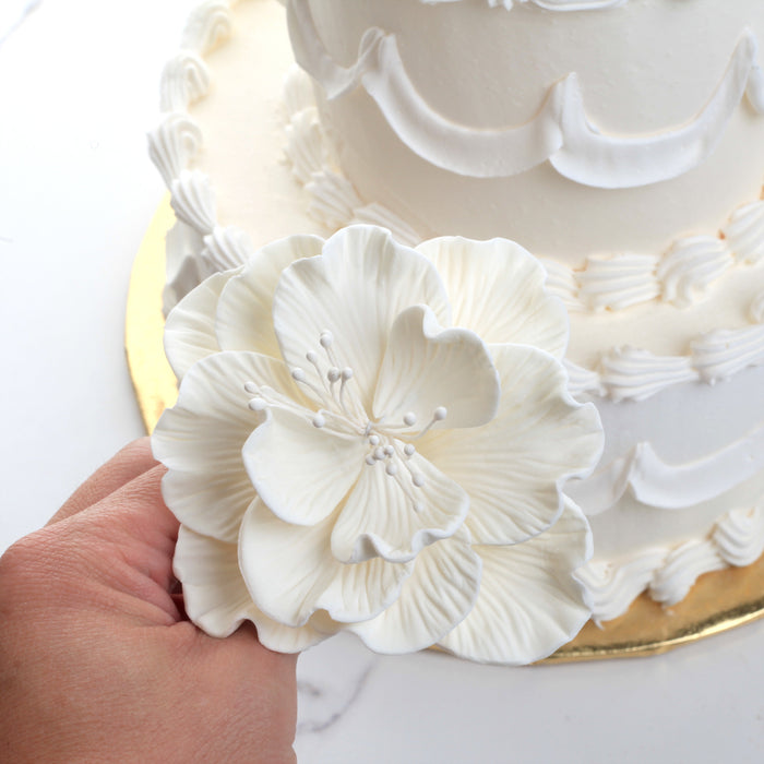 Multiple large white Cora peony gumpaste sugar flowers arranged together for tiered cake styling.