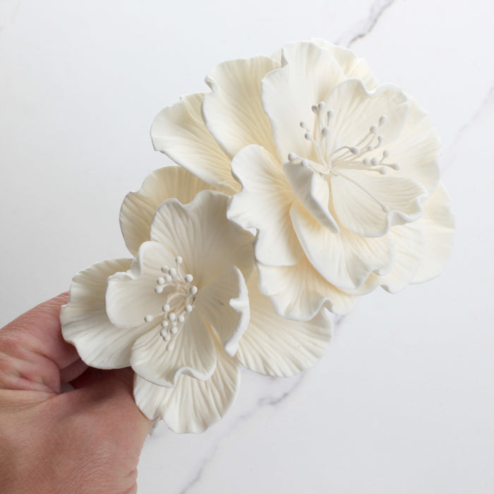 Multiple medium white Cora peony gumpaste sugar flowers arranged together for tiered cake styling.