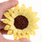 Close-up of delicate yellow gumpaste sunflower petals and dark brown seed center for rustic wedding cake decorating.