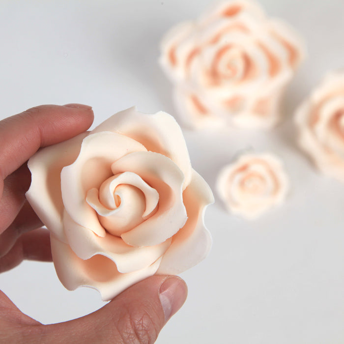 Elegant ivory sugar rose cake toppers arranged on a tiered fondant wedding cake for a timeless look.