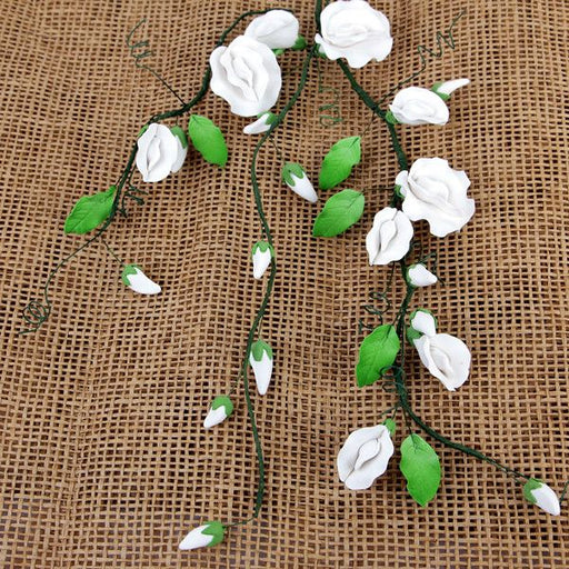 Handcrafted white and green gumpaste sweet pea sugar flower sprays on a burlap background for cake decorating by Caljava