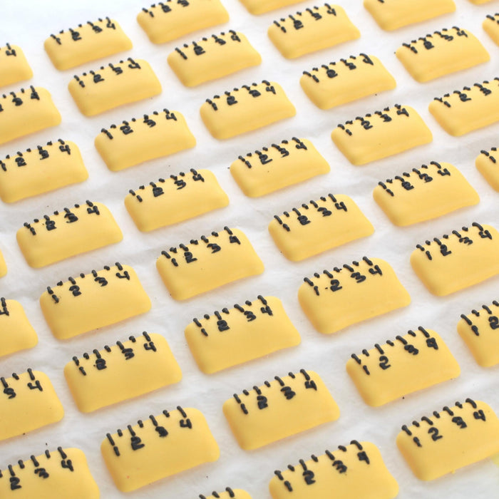 Back-to-school royal icing ruler and pencil decorations on chocolate treats, ideal for commercial bakeries targeting school fundraisers and events