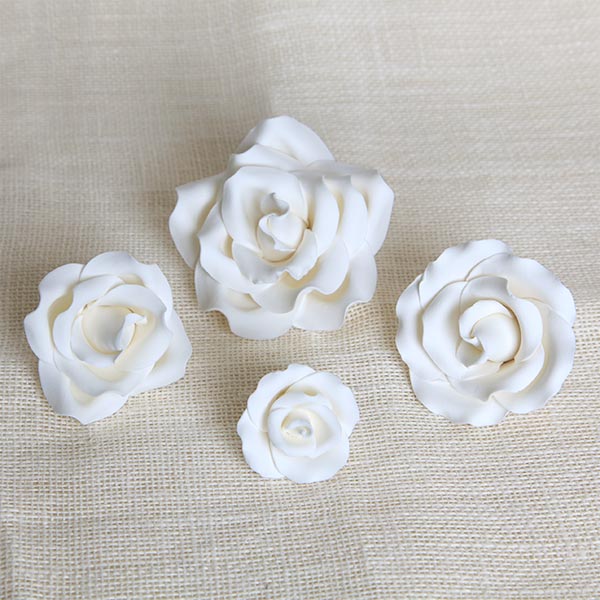 Handcrafted white English garden rose sugar flowers arranged on a multi-tiered fondant wedding cake.