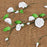 Detailed close-up of handmade white gumpaste sweet pea buds and green leaves wired for wedding cake design.