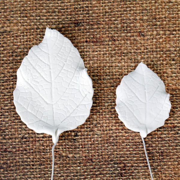 Close-up showing two sizes of green gum paste rose leaves with dimensions 2.5x1.75 inches and 1.5x1.25 inches with flexible wire stems.Wholesale cake supply.